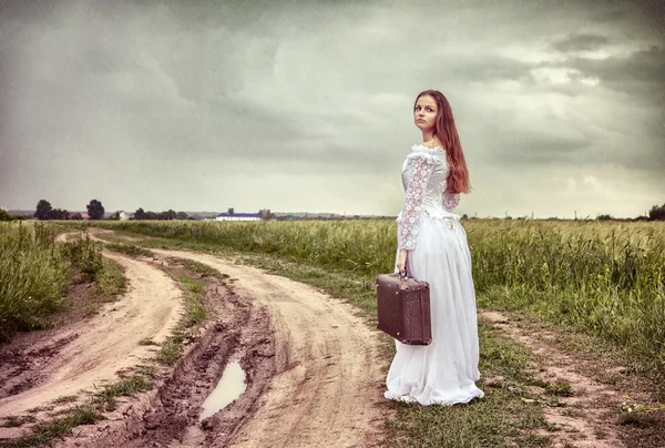 Обиженная невеста идет со старым чемоданом — стоковое фото