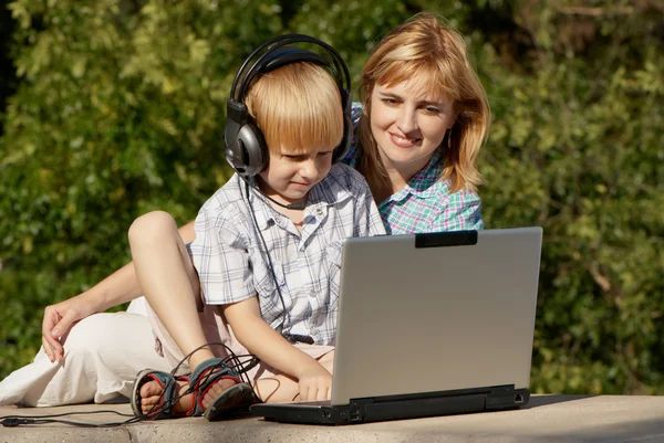 Le petit garçon et la mère avec l'ordinateur portable dans le parc — Photo