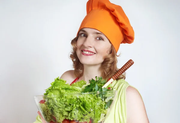 De prachtige kok met groene salade in handen — Stockfoto