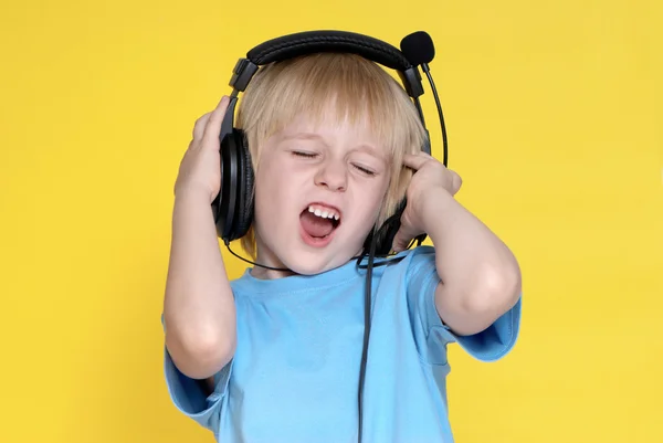 The emotional kid in ear-phones on a yellow background — Stock Photo, Image