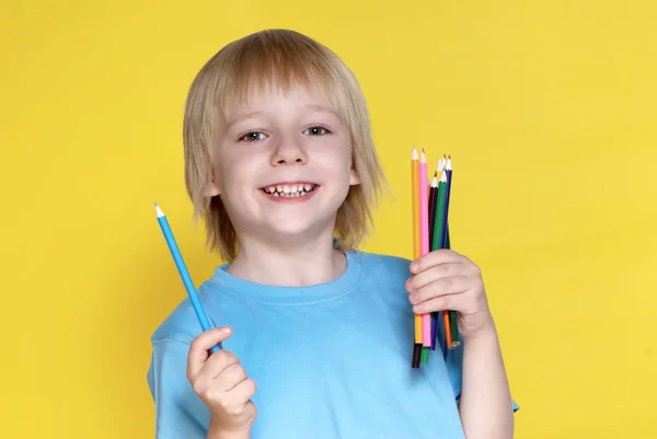 The small schoolboy with pencils on a yellow background — Stock Photo, Image