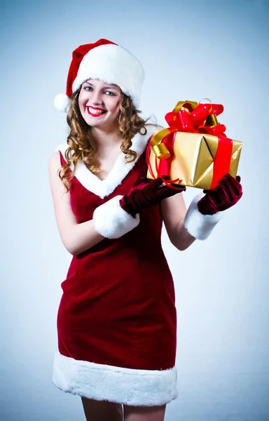 Beautiful woman in a red dress and hat of Santa with a big gift — Stock Photo, Image