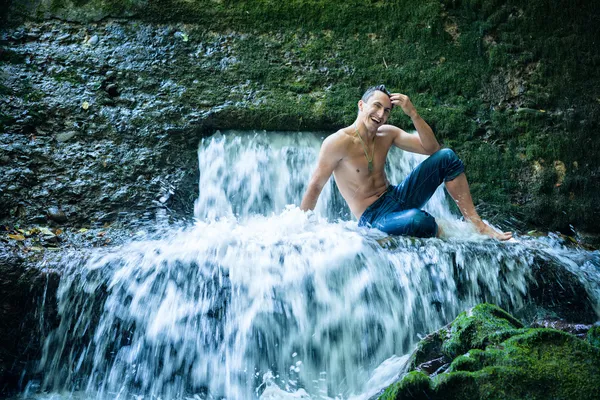 Gelukkig jonge man plezier en ontspannen onder de waterval. — Stockfoto