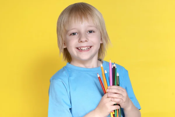 The small schoolboy with pencils on a yellow background Stock Photo