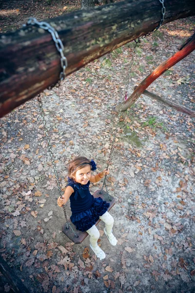 Gelukkig klein meisje glimlachen op swing — Stockfoto