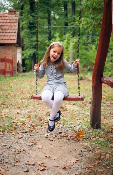 Menina sorrindo no balanço — Fotografia de Stock