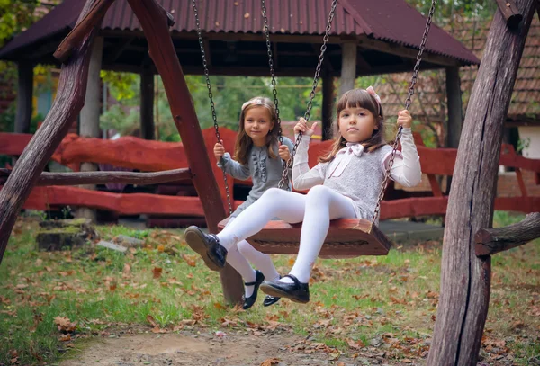 Girlfriends on swing in park — Stock Photo, Image