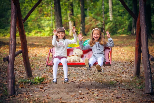 Girlfriends on swing in park — Stock Photo, Image