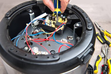 Tornavidayla elektrik tavasını tamir eden bir mühendisin elleri.