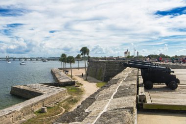 İspanyol sömürge topları eski bir İspanyol kalesinin tepesinde, bulutlu gökyüzü ve palmiye ağaçları, St Augustine, Florida, ABD.