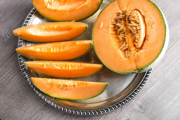 Ripe cantaloupe melon cut into slices with seeds. Melon on a platter.