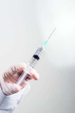 Doktorun elindeki eldivende gri arka planda tıbbi bir şırınga var. Hastaya tıbbi bakım ve ilaç konsepti. mesaj için yer. Boşluğu kopyala