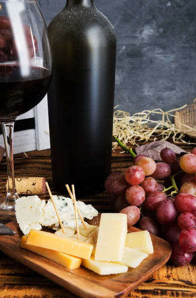 Bottiglia Polverosa Vino Rosso Antico Formaggio Uva Tavolo Legno Contro — Foto Stock