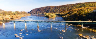 Mavi gökyüzünün altındaki nehir ve yol köprüsünün görüntüsü. Sonbahar manzarası. Harper Feribotu, Batı Virginia, ABD.