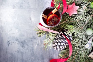 Baharatlı cam bardakta sıcak şarap. Gri masada sıcak bir Noel içeceği.