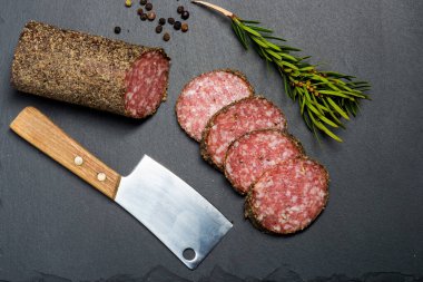 Baharatlı salam dilimlemek ve arka planda balta bıçağı. Yukarıdan görünüm