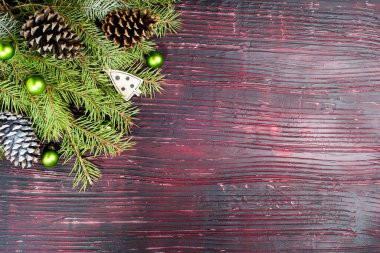 Kırmızı ahşap zemin üzerinde çam kozalakları olan ebedi yeşil kozalaklı dalların üst görünümü