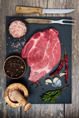 Taze et siyah tahta üst görüşünde. Pişirmek için çiğ biftek ve baharat.
