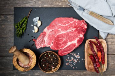 Taze et siyah tahta üst görüşünde. Pişirmek için çiğ biftek ve baharat.