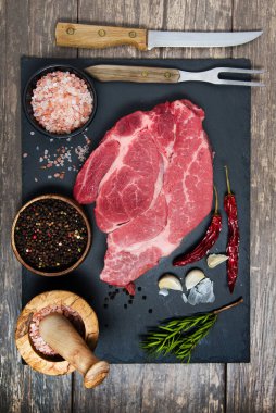 Taze et siyah tahta üst görüşünde. Pişirmek için çiğ biftek ve baharat.