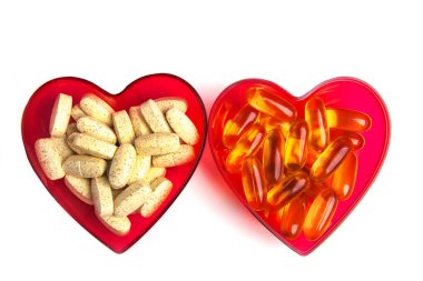 Kalbin iki yarısı haplar ve vitaminlerle dolu. Beyaz arkaplanda.