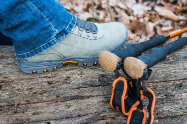 Yürüyüş botu içinde bir ayak kütüğün üzerinde duruyor. Direkler yakında..