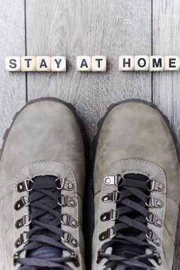 Stay at home - lettering made of cubes with letters. On the gray floor Gray boots.