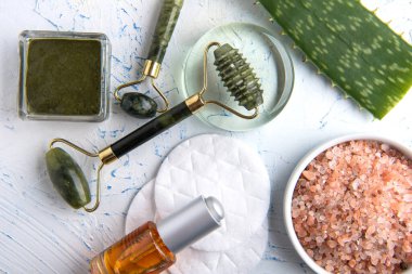 Yüz kremi ve yeşim masaj silindiri. Sağlıklı ve genç cilt için kaldırma. Beyaz arka planda organik kozmetik ürünler. Cilt bakımı moda. Yüz ve boyun masajı için Gouache kazıyıcı