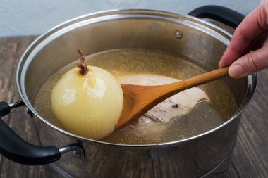 Tencerede et suyu çorbası ve ahşap kaşıkta haşlanmış soğan..