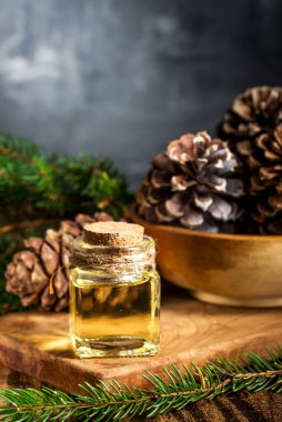 Ahşap zemin üzerinde küçük cam şişe içinde sedir ve ladin yağı. Seçici odaklanma. Metin için boşluk.