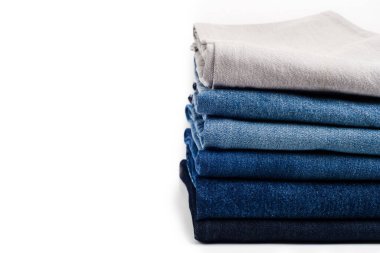 Beyaz arka planda farklı bir kot pantolon yığını. Metni kopyala.