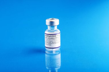  Mavi arka planda bir şişe Pfizer-BioNTech Covid-19 aşısı