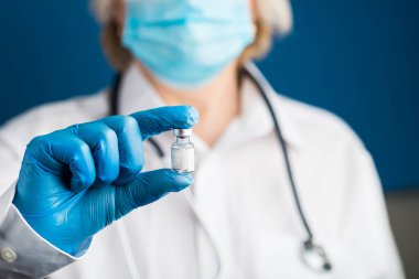 Doktor elinde aşı şişesi tutuyor. Laboratuvar fotoğrafı. Mavi eldivenli tıbbi eller antiviral aşı yapıyor...