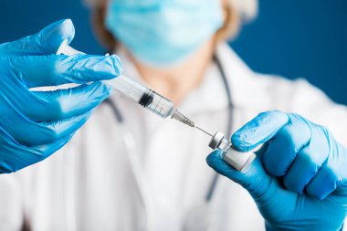 Tıbbi eldivenli bir doktorun elleri, Corona virüsü covid 19 'a karşı enjeksiyona hazırlanan bir şişeden sıvı bir aşı çeker. Coronavirüs aşısı için grip aşısı kavramı.