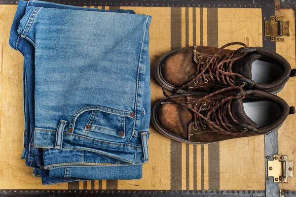 old boots and jeans on the background of a vintage suitcase. view from above,