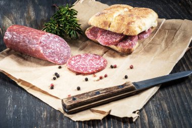 Kesik parçaları ve bıçakla ambalaj kağıdında salamlı sandviç..