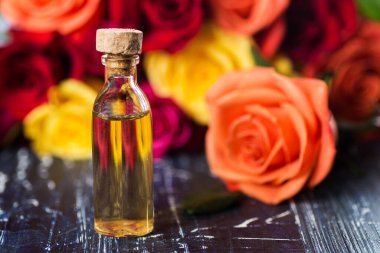 Taze güllerin arka planında cam şişe. Gül özlü serum ya da temel aromatik yağ