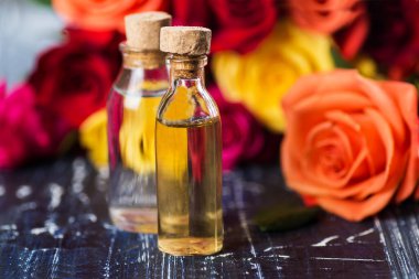 Taze güllerin arka planında cam şişe. Gül özlü serum ya da temel aromatik yağ.