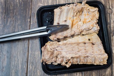 Pişirmek için hazırlanmış bir yemek tepsisinde haşlanmış et. Ahşap bir masada domuz pirzolası. Üst görünüm