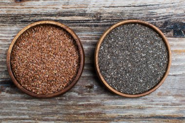 Keten tohumu ve tahta bir tahtanın üzerindeki tahta kaselerde Chia. Kopyalama alanı olan üst görünüm. Sağlıklı gıda konsepti.