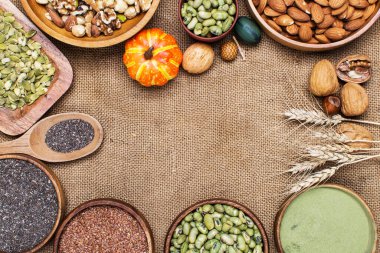 Tohumlar, süper yiyecekler, fındıklar, fasulyeler, bisküviler ve bir çuval bezi arkaplanda sağlıklı ve temiz yiyecek seçimi.