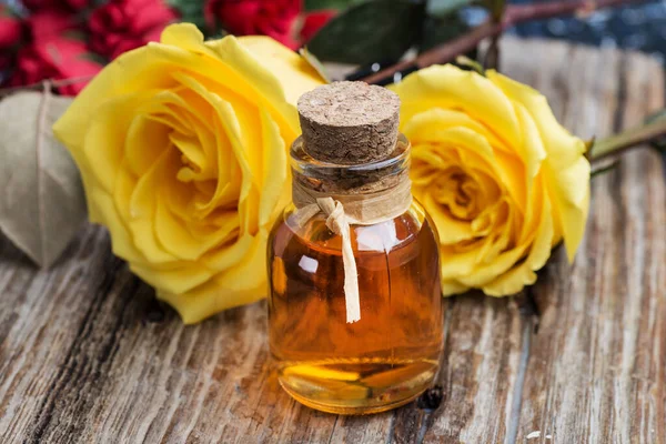 rose oil in a bottle close-up on a background of yellow roses.