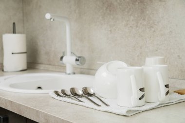 Kuru havlu ve temiz bulaşık takımları mutfak lavabosunun yanındaki beyaz tezgahta.