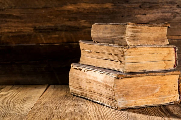 Eski ahşap bir masanın üzerinde üç eski püskü kitap yığını. Boşluğu kopyala