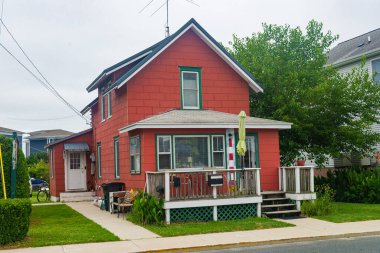 İki katlı küçük bir Amerikan evi, deniz kenarında bir köyde bakımlı bir çimleri var..