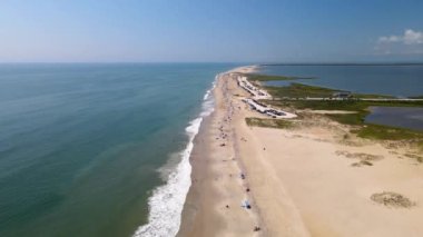 Chincoteague Adası Virginia sahilinin yukarıdan aşağı manzarası. Atlantik Okyanusu kıyısındaki plajda araba park ediyor. Sahil boyunca sahil insanları ve çadırlar, vahşi yaşam sığınağı ve turizm beldesi.
