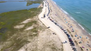 Chincoteague Adası Virginia sahilinin en alt manzarası. Atlantik Okyanusu kıyısındaki plajda araba park ediyor. Sahil boyunca sahil insanları ve çadırlar, vahşi yaşam sığınağı ve turizm beldesi.