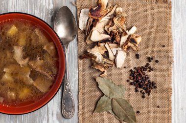 Kurutulmuş porcini mantarlı mantar çorbası defne yaprağı ve kırsal masa dokusu arka planında biber. Yukarıdan görüntüle.