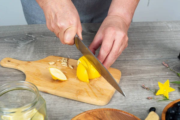 Frauenhände Schneiden Zitrone Mit Messer Auf Schneidebrett — Stockfoto