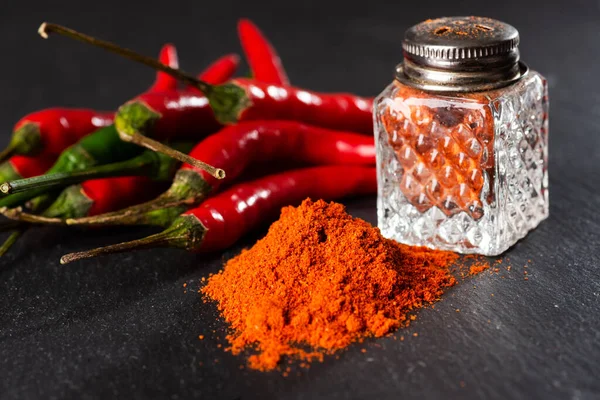 bunch of red peppers, capsicum and pepper pot on a black table. Close-up. Selective focus. Space for text.